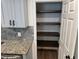 A pantry with wooden shelves provides ample space for food storage next to kitchen cabinetry and countertops at 1526 Cordova Ave, Holly Hill, FL 32117