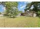 Cozy single-story home featuring a green lawn with mature trees providing shade at 205 W Division St, Deland, FL 32720