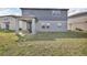 A view of a gray two-story home showing a covered patio and spacious backyard at 2210 Derwent Dr, Davenport, FL 33896