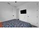 Minimalist bedroom features a floral bedspread, flat-screen TV, and two doors for easy access at 2210 Derwent Dr, Davenport, FL 33896