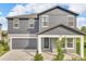 Charming two-story home with blue siding, a gray garage door, and a covered front porch at 2210 Derwent Dr, Davenport, FL 33896