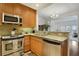 Eat-in kitchen featuring stainless steel appliances, wood cabinets, and an open view to the living room at 2305 Edgewater Dr # 1613, Orlando, FL 32804