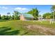 Charming tan home with vibrant blue door, green roof, and spacious front yard, nestled among lush greenery at 287 Hilltop Dr, Longwood, FL 32750