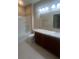 A well-lit bathroom features a single sink, granite countertops, a large mirror, and tub with shower at 2983 Boating Blvd, Kissimmee, FL 34746