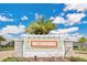 A clear view of the Waterbrooke community sign framed by lush greenery and palm trees under a bright, sunny sky at 3280 Canna Lily Pl, Clermont, FL 34711