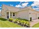 Exterior view of home featuring manicured lawn and garden, attached two-car garage, and covered entryway at 3280 Canna Lily Pl, Clermont, FL 34711