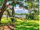 Scenic backyard view with lush lawn, mature trees, and private dock on the serene lake, offering tranquility at 3443 S Mellonville Ave, Sanford, FL 32773