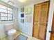 Simple bathroom with a toilet, window, louvered closet, and decoratively painted accent squares at 3443 S Mellonville Ave, Sanford, FL 32773