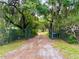 A gated entrance and long driveway, canopied by mature trees, creates a private arrival to the property at 3443 S Mellonville Ave, Sanford, FL 32773