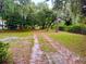 Long gravel driveway surrounded by trees and greenery, leading to the home, situated on a spacious lot at 3443 S Mellonville Ave, Sanford, FL 32773
