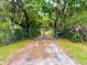 Gated entrance to private property lined with mature trees and lush greenery, providing a secluded and secure setting at 3443 S Mellonville Ave, Sanford, FL 32773