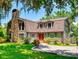 Charming exterior of home with a stone chimney, wood siding, and a well-manicured lawn at 3443 S Mellonville Ave, Sanford, FL 32773