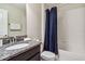 Well-lit bathroom with granite countertop, shower with blue curtain, and white tiled walls at 4740 Sleepy Hollow Dr, Kissimmee, FL 34746