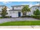 Two-story white home with a paved driveway, attached garage, blue front door, and palm tree at 4740 Sleepy Hollow Dr, Kissimmee, FL 34746