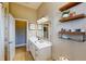 Bright bathroom featuring a white vanity, decorative mirror, and stylish open shelving at 6198 Linneal Beach Dr, Apopka, FL 32703