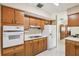 Classic kitchen design with wood cabinets, a white refrigerator and stove, and floral wallpaper at 620 Marshall St, Altamonte Springs, FL 32701