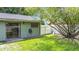 Green house exterior featuring sliding glass door, small window, and well-kept lawn at 620 Wood Dr, Kissimmee, FL 34759