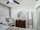 Bedroom showcasing a decorative ceiling fan, comfortable armchair, and a stylish wooden dresser with mirror at 620 Wood Dr, Kissimmee, FL 34759