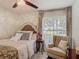 Bright bedroom with a decorative headboard, a ceiling fan, and a comfortable sitting area by the window at 620 Wood Dr, Kissimmee, FL 34759