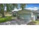 Front view of a well-kept home, featuring a clean garage door, a welcoming entrance, and a green lawn with a mature tree at 620 Wood Dr, Kissimmee, FL 34759