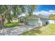 Charming home featuring a spacious driveway, well-manicured lawn, and classic architectural details, shaded by a mature tree at 620 Wood Dr, Kissimmee, FL 34759