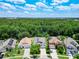An aerial view of homes in a lush, green neighborhood with many trees and blue skies at 6843 Cherry Grove Cir, Orlando, FL 32809