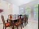 Dining room with a wooden table and eight chairs, tile floors, and three large windows with natural light at 6843 Cherry Grove Cir, Orlando, FL 32809