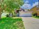 Inviting home with lush greenery and a well-maintained lawn leading to a two-car garage at 6843 Cherry Grove Cir, Orlando, FL 32809