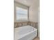 Bathroom featuring a luxurious white soaking tub with modern fixtures and a view from the window at 8230 Corkfield Ave, Orlando, FL 32832