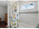 Modern bathroom featuring white marble walls, a tub with shower, a window with blinds and decorative shower curtain at 8418 Via Bella Notte, Orlando, FL 32836