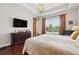 Bright main bedroom with hardwood floors, dresser, flat screen tv, large window with blinds and overhead chandelier at 8418 Via Bella Notte, Orlando, FL 32836