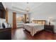 Spacious main bedroom featuring hardwood floors, tray ceiling, a large window and decorative chandelier lighting at 8418 Via Bella Notte, Orlando, FL 32836