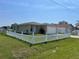 A single-story home surrounded by a white picket fence and lush green grass at 909 San Paulo Way, Kissimmee, FL 34758