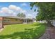 Expansive backyard showcasing a green lawn, mature trees providing shade, and a clean white fence at 1017 Manchester Cir, Winter Park, FL 32792