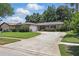 Charming single-story home features a well-manicured lawn, mature trees, and a long concrete driveway at 1017 Manchester Cir, Winter Park, FL 32792