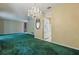 Bright living room with green carpet, decorative chandelier, and white refrigerator at 1017 Manchester Cir, Winter Park, FL 32792