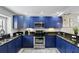 Modern kitchen featuring bright blue cabinetry, granite countertops, and stainless steel appliances at 14501 Damai Ln, Orlando, FL 32821