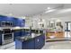 Open-concept kitchen with blue cabinets and stainless steel appliances, leading into the dining and living areas at 14501 Damai Ln, Orlando, FL 32821