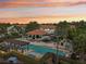 Beautiful swimming pool at dusk with lounge chairs, pergola, pavilion, palm trees and lush landscaping at 14501 Damai Ln, Orlando, FL 32821