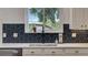 Modern kitchen featuring sleek white cabinets and backsplash with black and gray patterned tile at 245 Via Siena Ln, Lake Mary, FL 32746