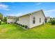 Well-maintained backyard with lush lawn, decorative bushes, and home's exterior with siding at 2528 Buttonwood Run, The Villages, FL 32162