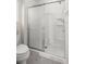 Bathroom showing a white toilet and a shower with silver trim and a sliding glass door at 2528 Buttonwood Run, The Villages, FL 32162