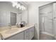 Bathroom featuring a dual sink vanity, neutral walls, shower with glass enclosure, and storage at 2528 Buttonwood Run, The Villages, FL 32162