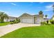 A well-kept home with an attached two-car garage, lush landscaping, and verdant green lawn at 2528 Buttonwood Run, The Villages, FL 32162