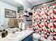 Well-lit bathroom features a blue vanity, patterned shower curtain, and decorative artwork, creating a stylish space at 2771 Ne 66Th St, Ocala, FL 34479