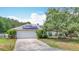 Charming single-story home with a well-manicured lawn, mature tree, solar panels, and a two-car garage at 2771 Ne 66Th St, Ocala, FL 34479