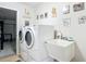 Convenient laundry room equipped with modern washer, dryer, utility sink and decorative wall art at 2771 Ne 66Th St, Ocala, FL 34479