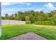 Backyard with green grass area bordered by a white fence and lush hedge row at 2914 Scarlett Dr, St Cloud, FL 34772