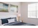 This bedroom features a window with blinds, two framed pictures, a blue comforter, and a white headboard at 2928 Buccaneer Palm Rd, Kissimmee, FL 34747