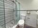 Bathroom with a glass shower, pebble floor, and white textured tile at 3034 Parkway Blvd # 102, Kissimmee, FL 34747